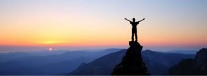 Man standing on mountain top looking over a sunset, words of possibility