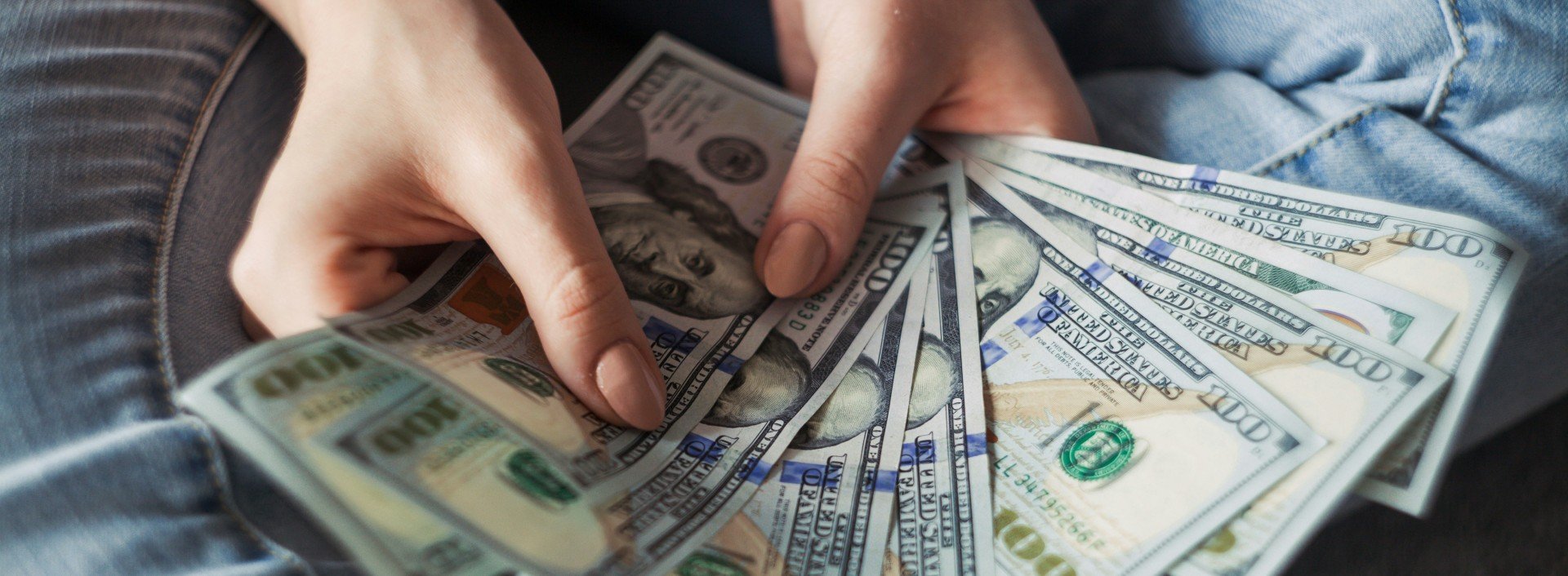 Money Slang in English: a woman's hands fan out $100 bills
