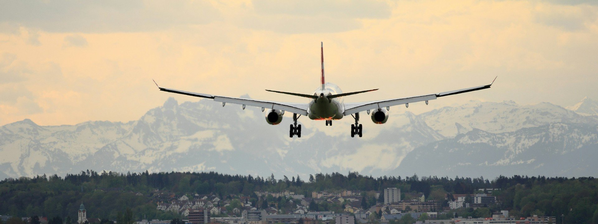 Airport vocabulary: a plane lands at an airport with mountains in the background.