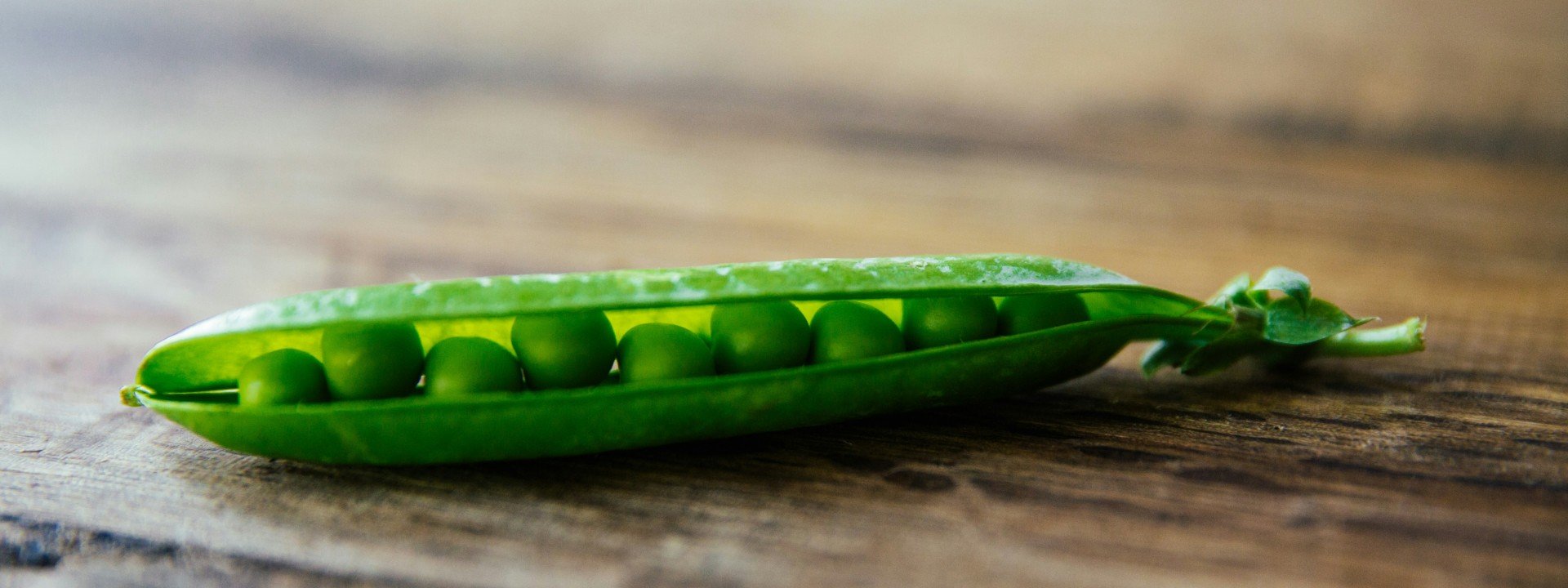 Food idioms in English: peas are nestled together in a pod on a table.