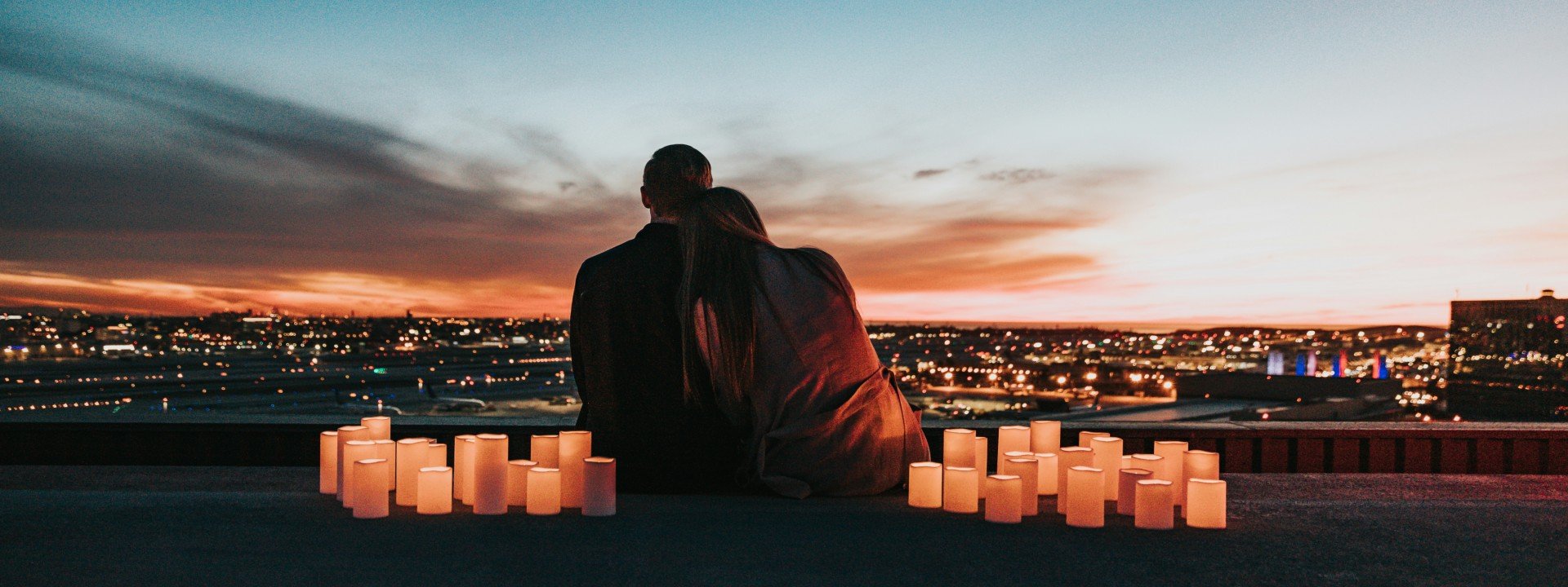 Date night vocabulary: a couple sits together watching the sunset surrounded by candles.
