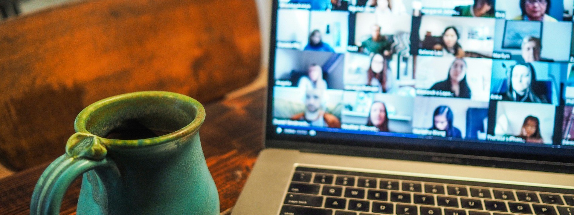 Phrases for Conference Calls: a mug of coffee sits next to a laptop where someone is in a conference call
